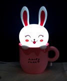 Настольная лампа-ночник «Счастливый кролик» EX-1101А Ночник для детской комнаты в виде улыбающегося кролика, выглядывающего из кружки, непременно понравится малышу, прекрасно впишется в интерьер и создаст приятный световой нюанс. 